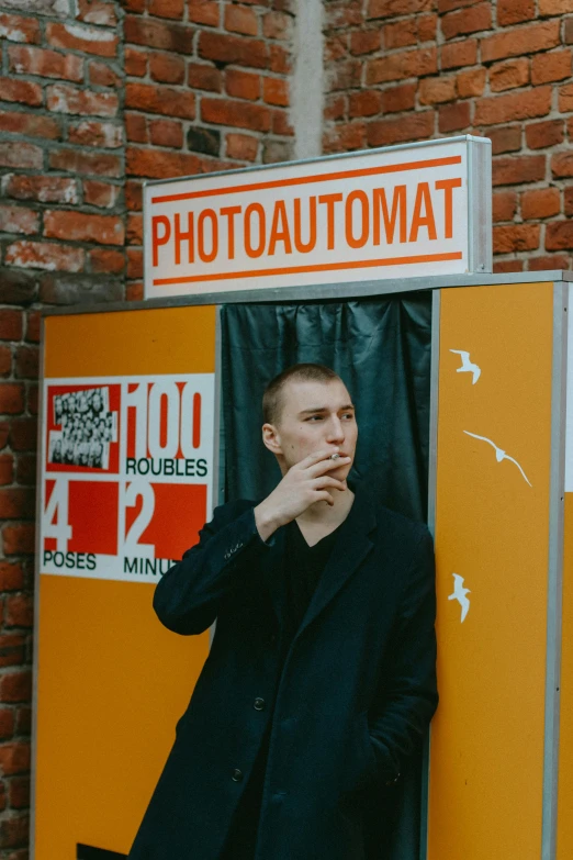 a man in black coat posing for picture at booth