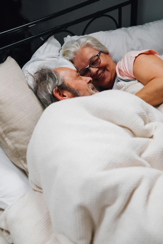 a woman with glasses is snuggled up next to an older woman in bed