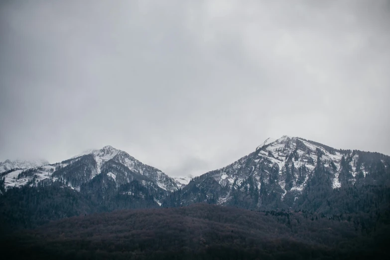 the mountains are covered in snow against a cloudy sky