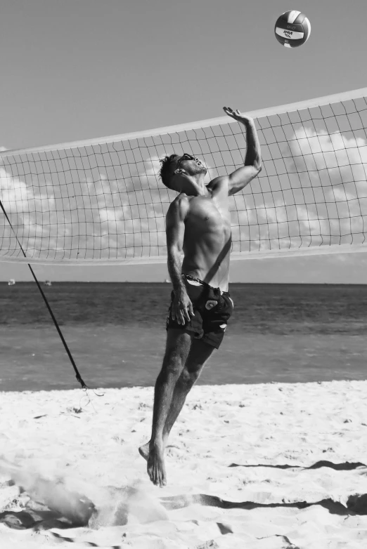 a man with a volleyball hits the ball over a net