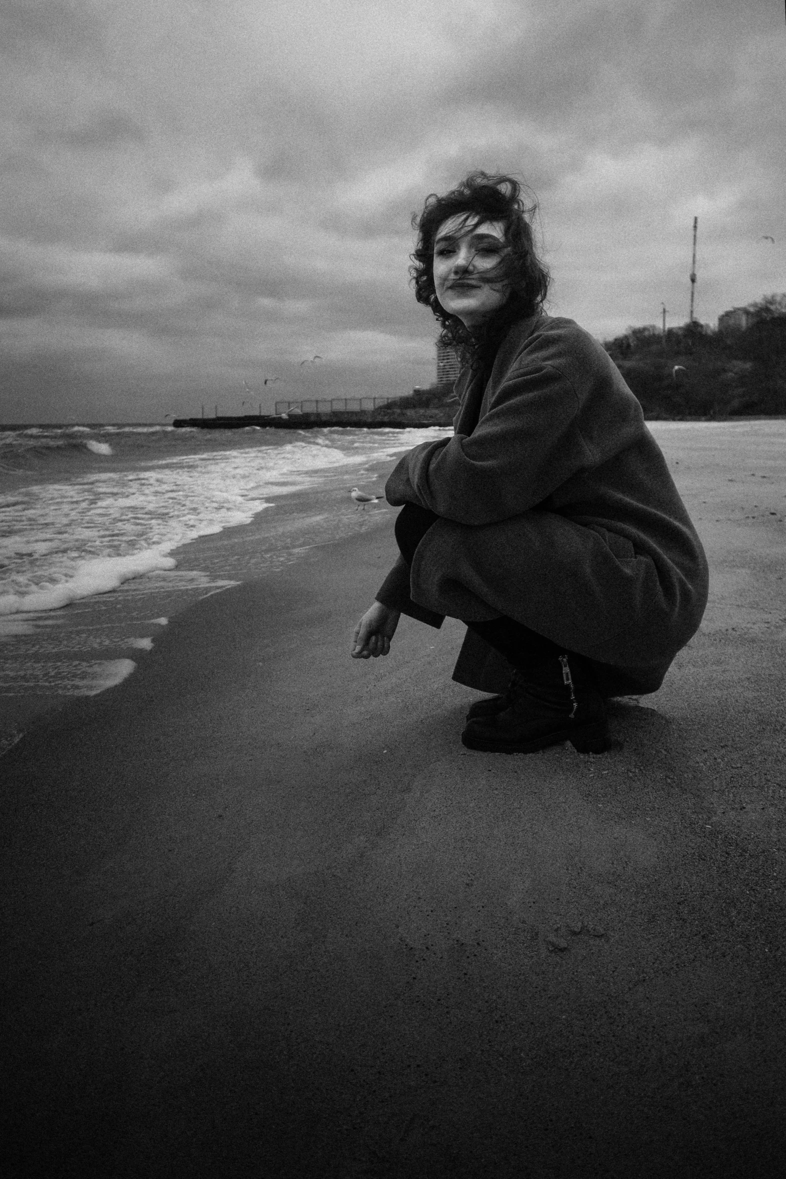 woman crouching in front of a body of water