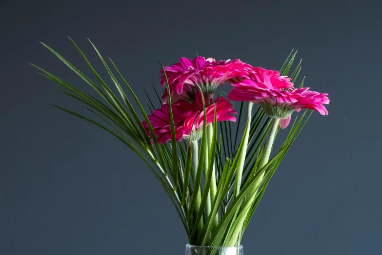 a green vase with pink flowers and grass