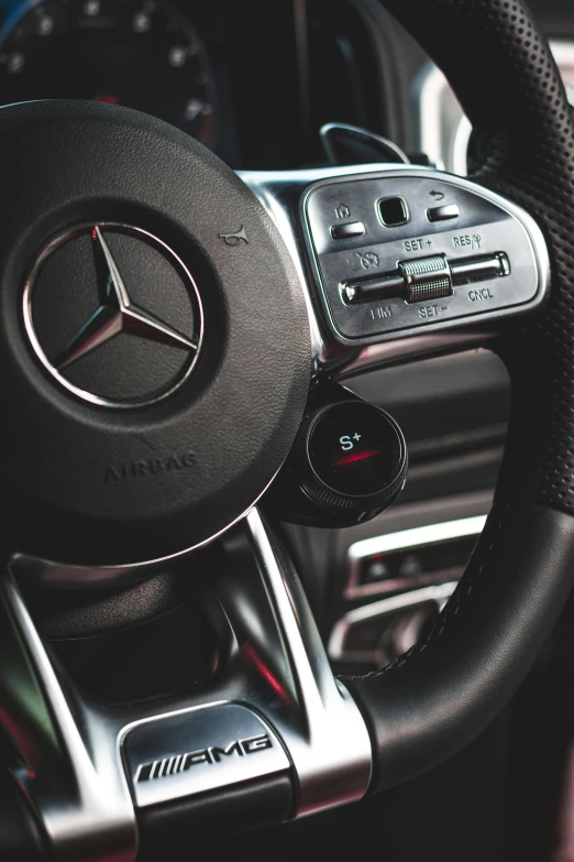 steering wheel view of a mercedes car with a black steering  and controls