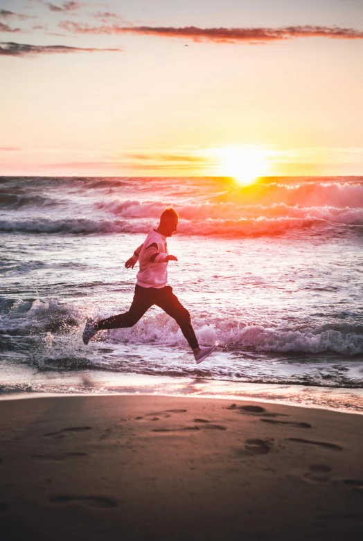 a man running along the beach at sunset