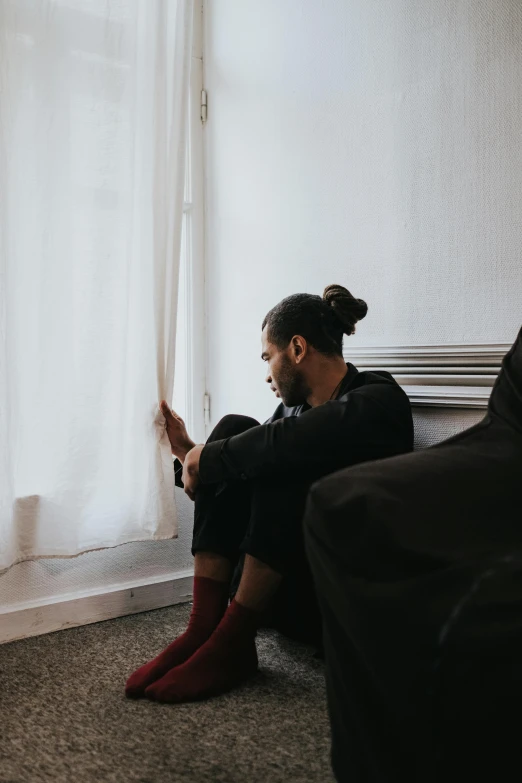 a man in black shirt and socks sitting on a couch