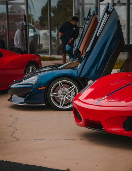 the two sport cars are parked together, with doors open