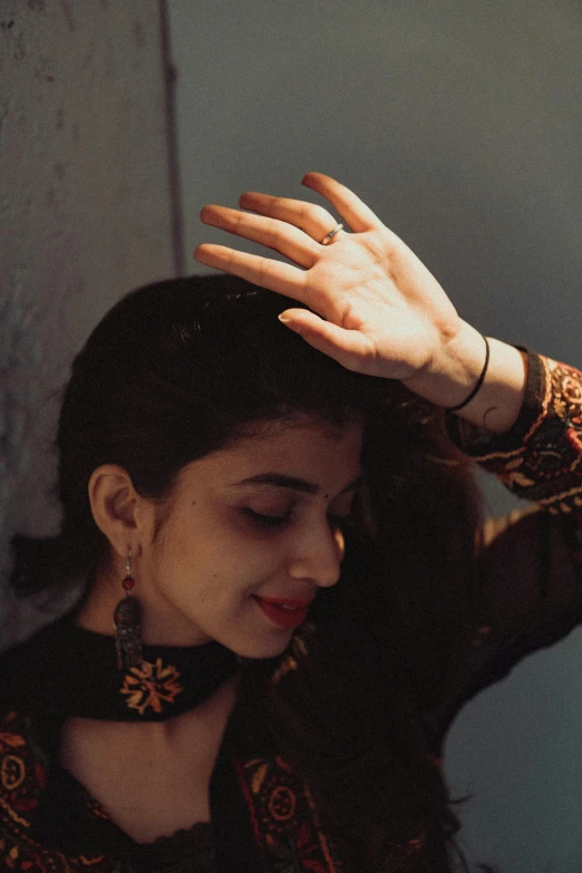 a woman wearing an elaborate dress and jewelry holds her hands over her head