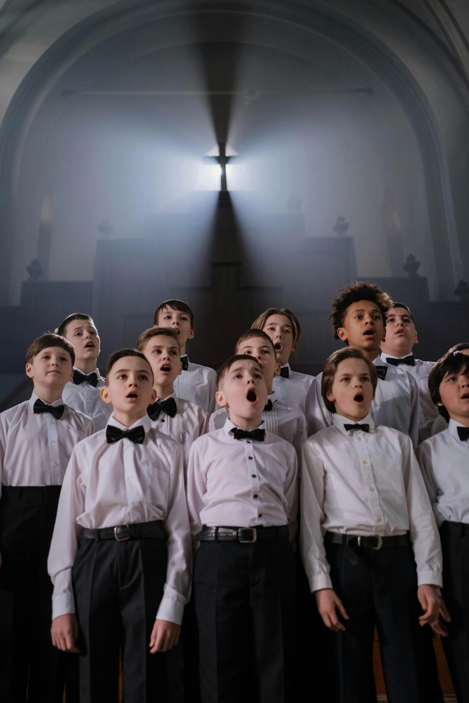 a group of young children standing next to each other in front of a cross