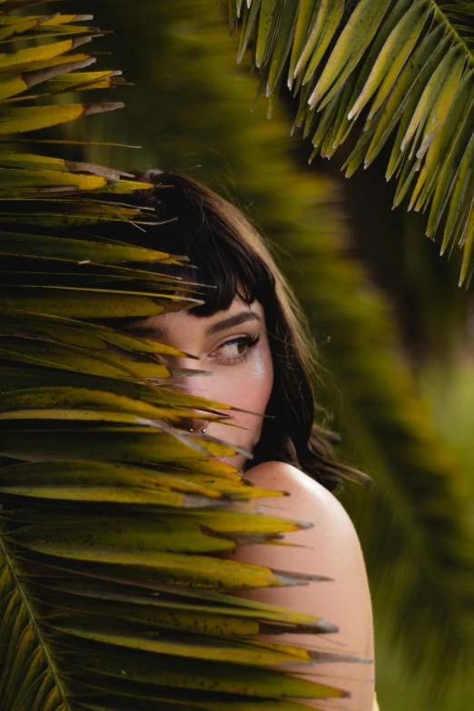 the woman is hiding behind the leaves in the grass