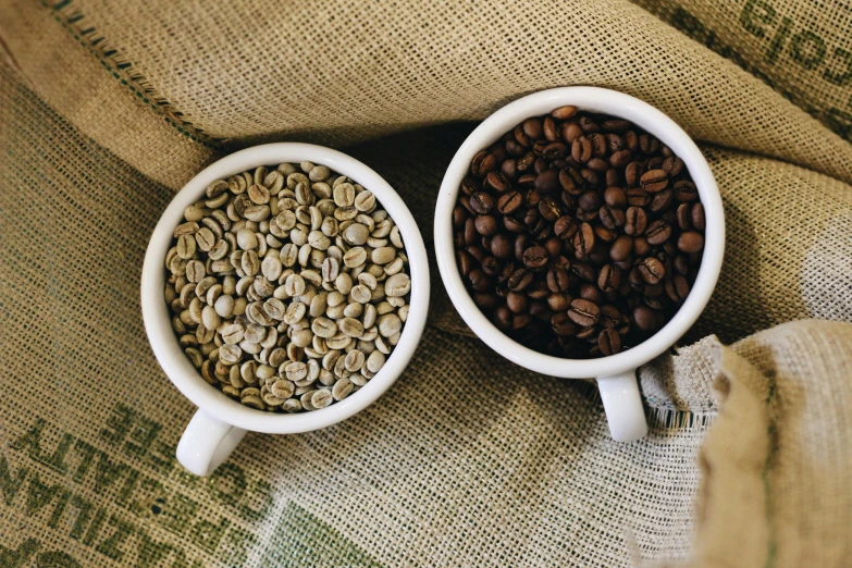 two cups filled with coffee beans are sitting on a couch