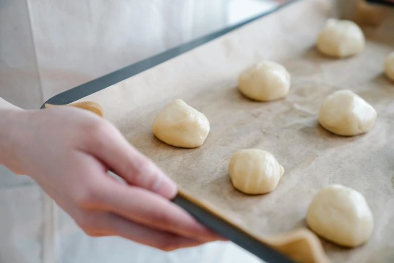 someone's hands are placing dough on a tray