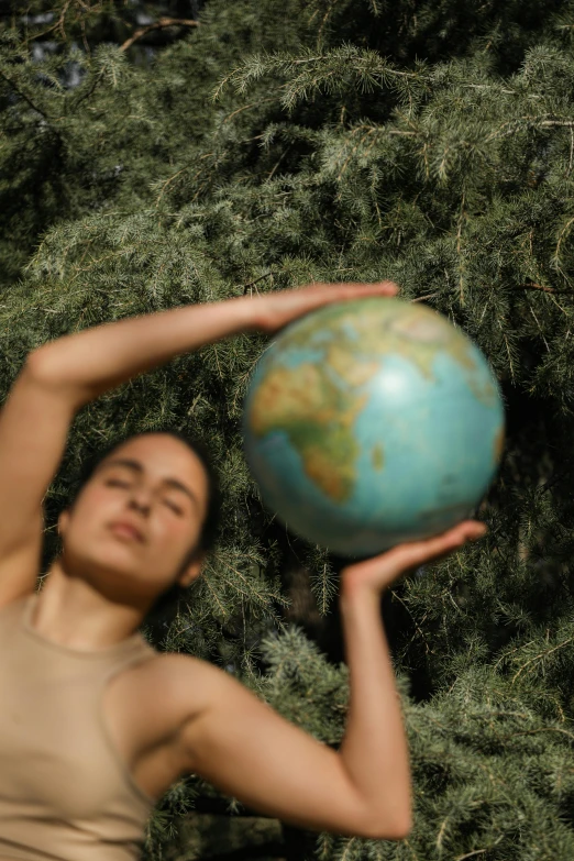 woman looking up to the sky holding a blue earth in her hands