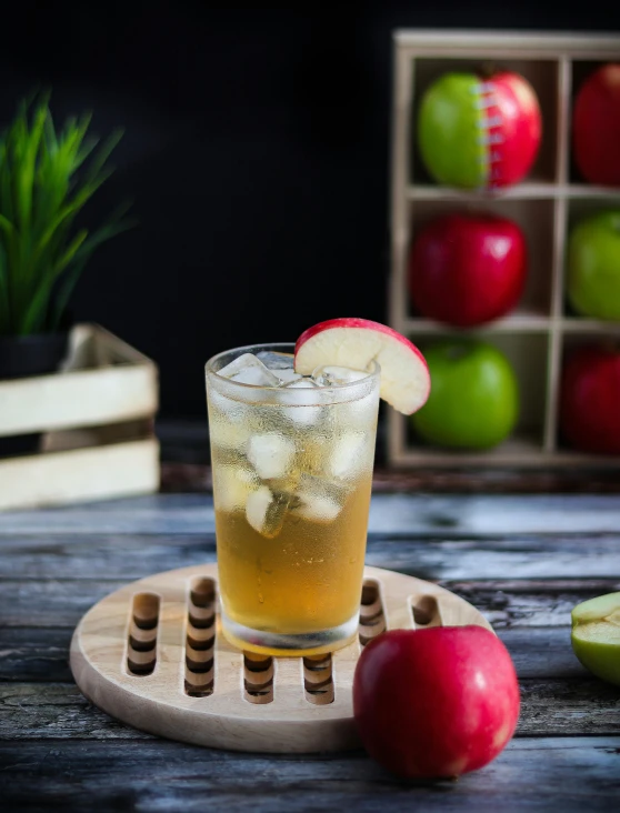 a glass filled with water next to apples