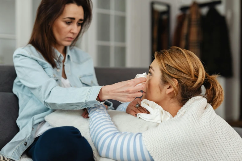 a woman being assisted by her mother as she gets the temperature taken