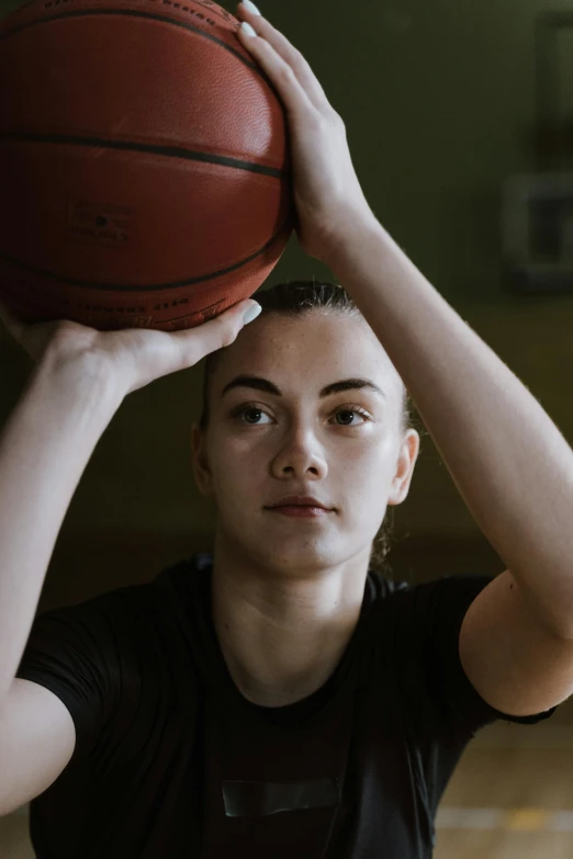 a woman holds up a basketball while posing for a po