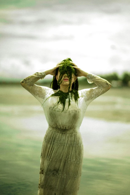 a woman in an unusual white dress with grass growing on her head