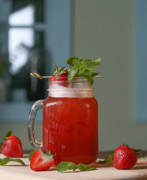 a pitcher of liquid, strawberries and mint with the lid open