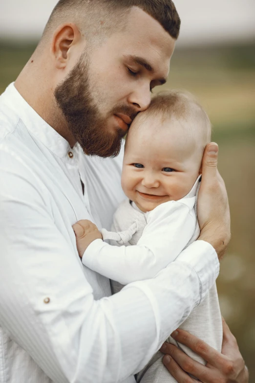 a man smiles as he hugs a small baby