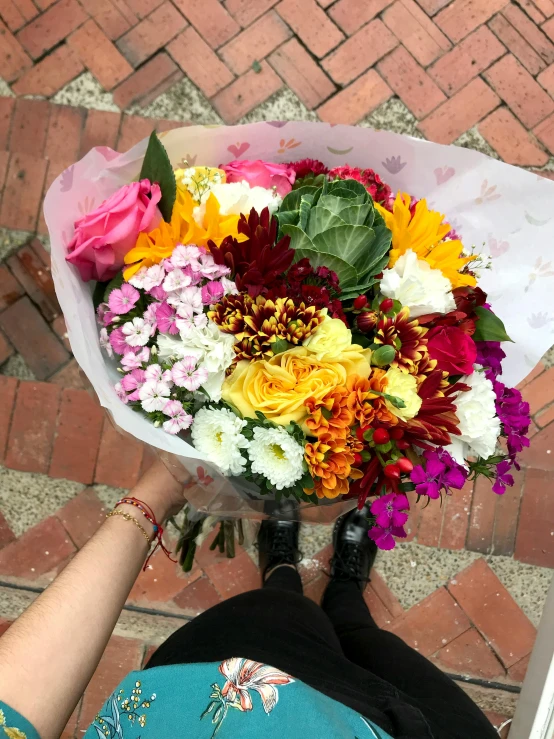 the person's hand holds a large bouquet of flowers