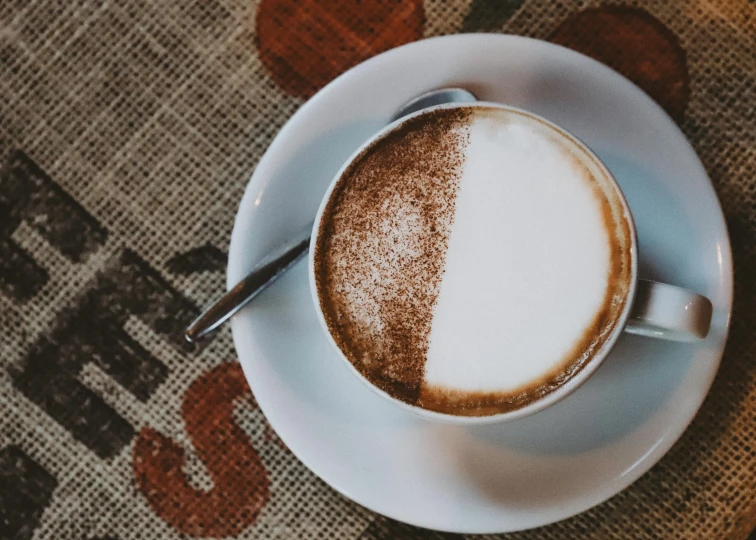 a cup of coffee and a spoon sitting on top of a white plate