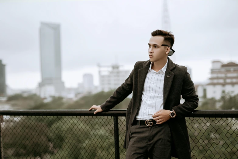 young man leaning on fence overlooking a city