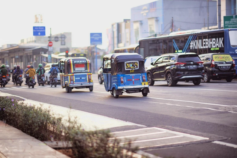 three motorcycles driving down a city street with people on it