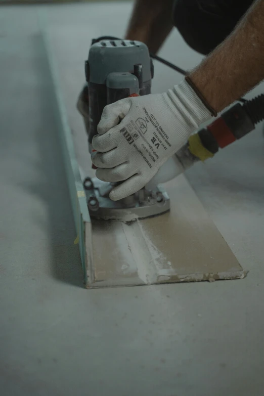 the person in the white gloves holds a hammer and polishing material on the floor