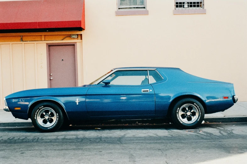 a blue muscle car parked in front of a garage