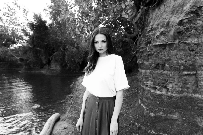 a woman poses next to some water in the sun