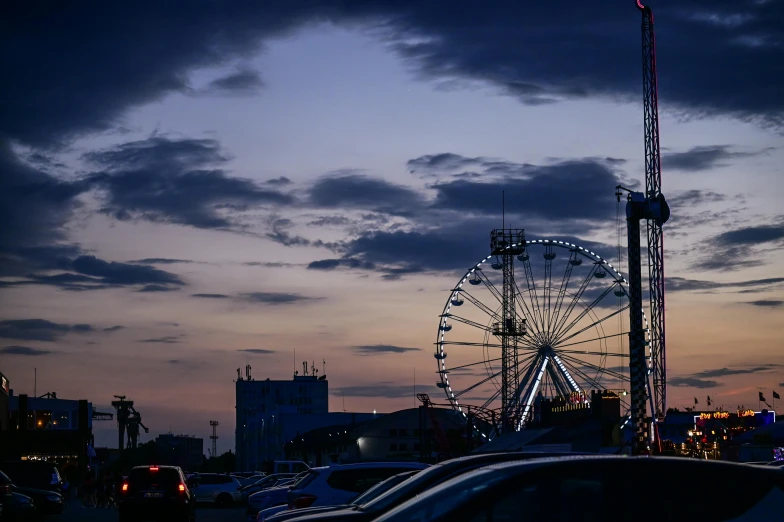 a ferris wheel in the distance as it sits next to a tall pole