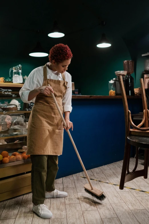 a woman cleaning a wood floor with a dust pan