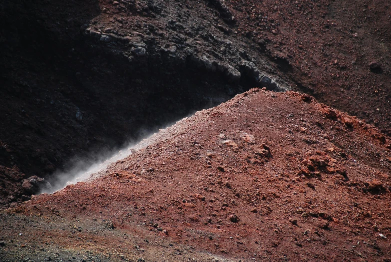 there is a black fire hydrant on a dirt hill