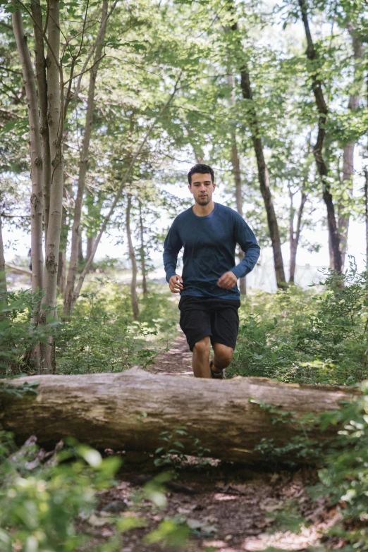 man running in wooded area while barefoot on trail