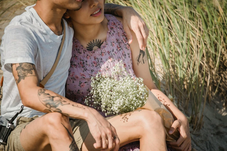 a young man hugging a woman sitting in a field of tall grass