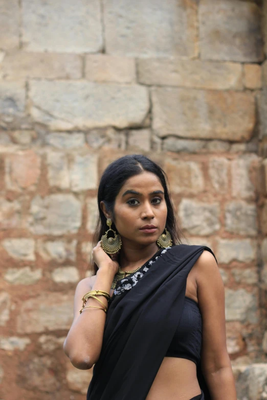 a woman in a sari is posing by some brick wall