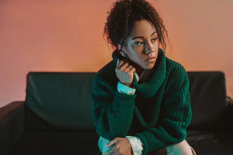 a woman in a green sweater sitting on a couch