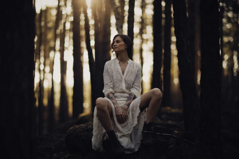 a woman sitting on the ground in a forest