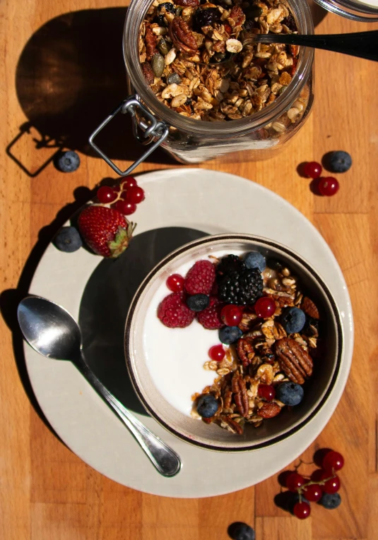 a plate topped with granola and berries next to a jar