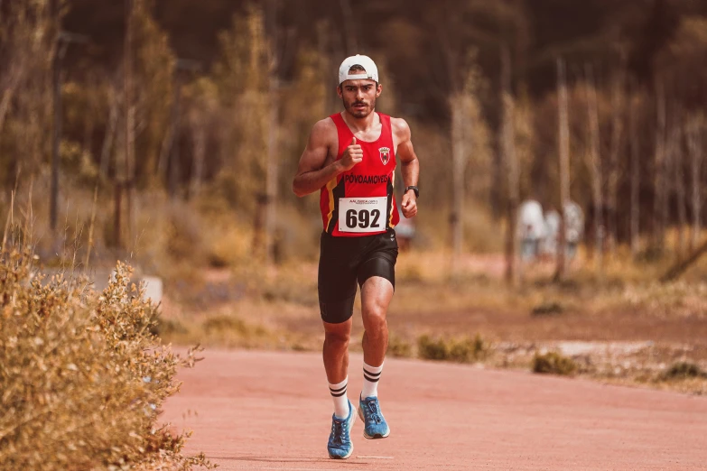 a man wearing a hat and running on a path