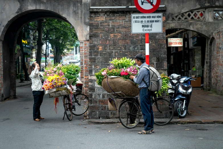 there are people standing around with bicycles, and flowers