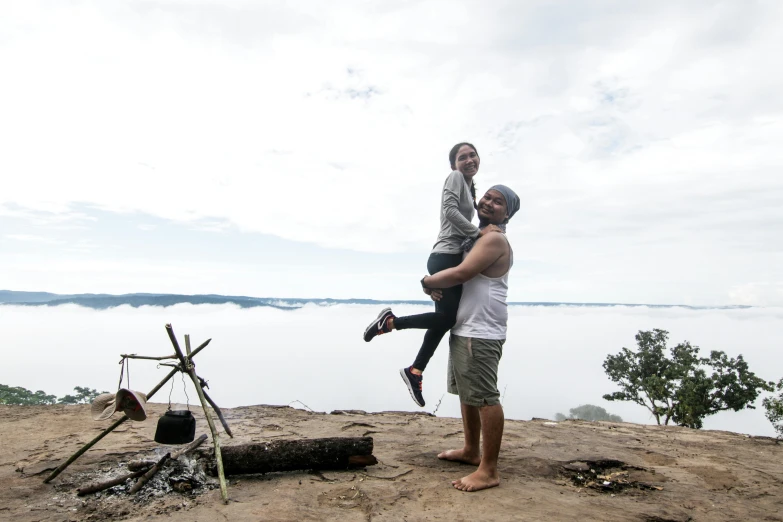 two people standing in the sand near a lake