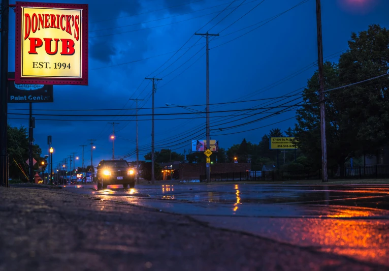 there is a sign for the drive thru pub on a rainy night