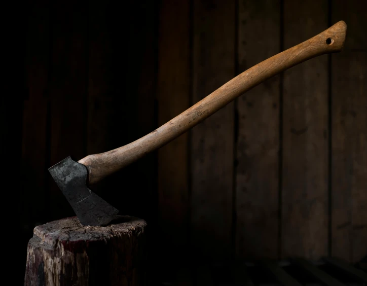 an old axg on a tree stump in a dark room