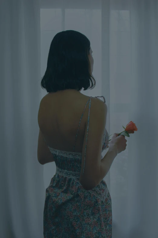 the woman with her back to the camera holding a flower