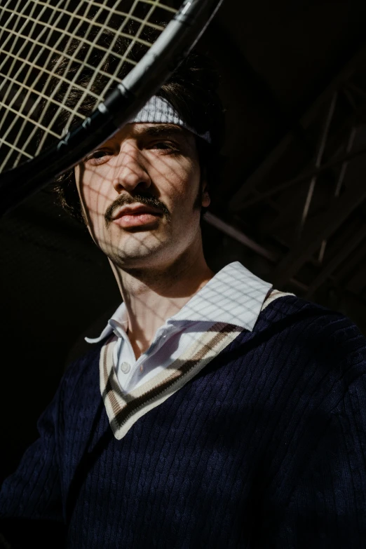 a man holding a tennis racket and wearing a hat