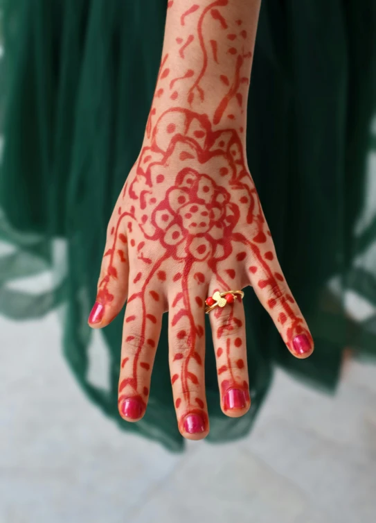 hand with henna tattoo designs and red nail polish