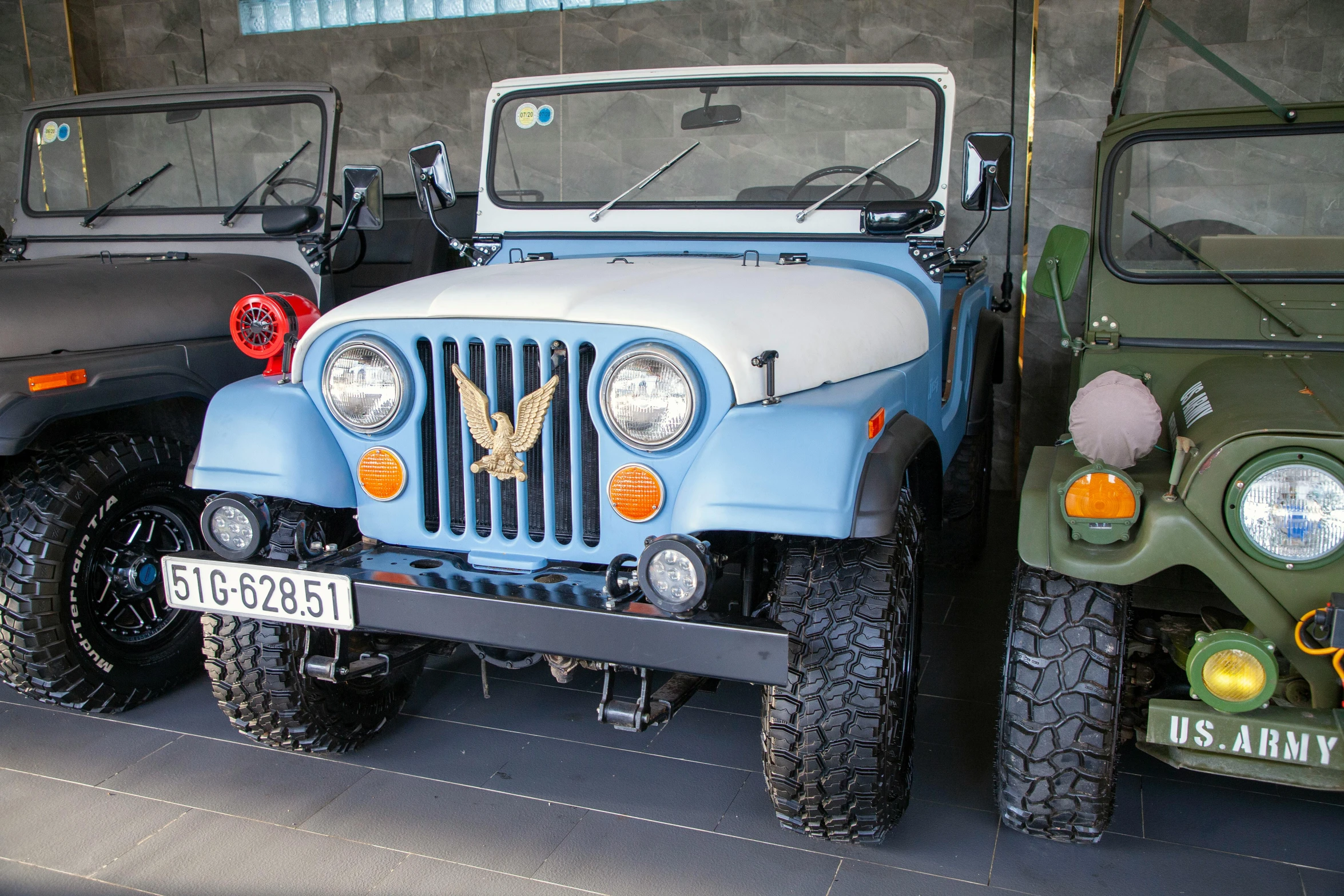 some jeeps and two jeeps sit parked next to each other