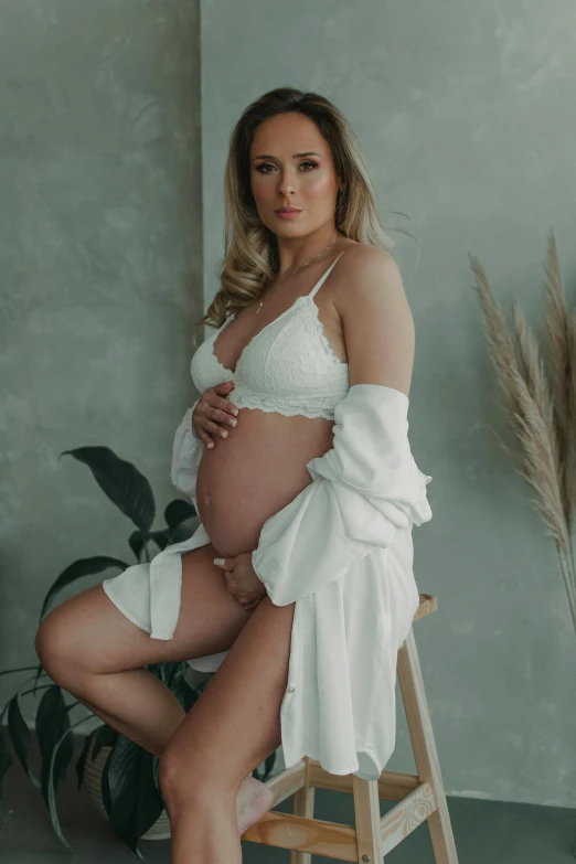 a pregnant woman in a white swim suit posing