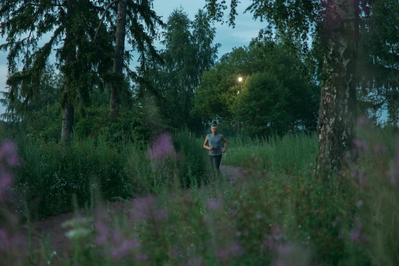 a man is running in a field next to the woods