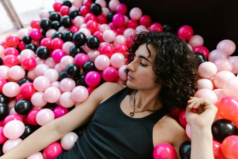 a woman lays down next to balloons in a ball pit